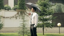 a smiling man standing under an umbrella in the rain 