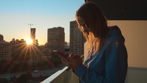 Woman on phone at sunset in a city setting