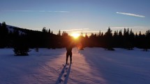 man hiking in snow at sunset 
