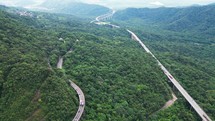 Drone flying above winding road during sunlight, Winding asphalt road through tropical rainforest. Countryside landscape. Aerial shoot reveal of a Highway in the forest
