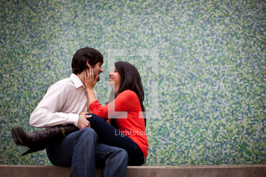 woman sitting in a man's lap with her hands on his face