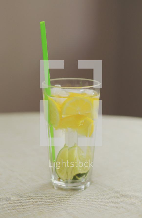 lemons and lime in water with a straw