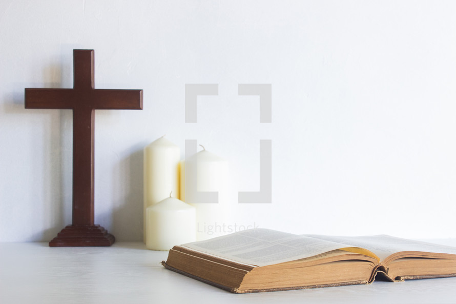 wooden cross, candles, and open Bible 