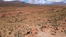 Aerial shot drone orbits to left around rock formation in desert
