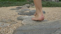 barefoot woman walks through rock garden close up on feet