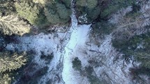 Drone Ascends On Snow-Covered Forest Mountains With Icy River. Aerial Orbit