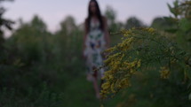 Woman walking through field of flowers passes in front of golden rod flower
