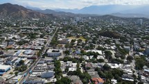 Aerial shot drone flying out of the city toward the mountains.