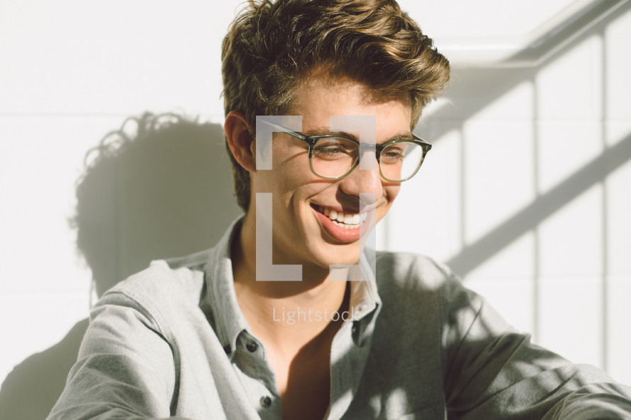smiling face of a young man in reading glasses 