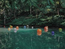 balls floating in a swimming hole 