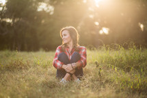 woman wearing a plaid shirt sitting in grass 