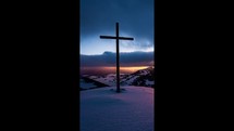 Vertical video of Colorful sunset over winter countryside nature with religious christian steel cross in top of snowy hill with fast clouds sky Time lapse