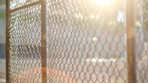 Sunshine through a chain link fence at a baseball field.