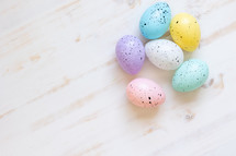 speckled Easter eggs on white wood background 