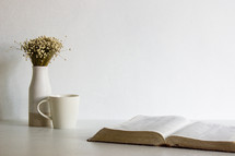 open Bible, vase, and coffee cup 