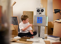 a boy building a cardboard robot 
