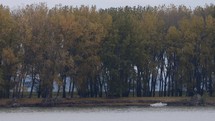 Boat Docked On The Side Of Danube River In Galati, Western Moldavia, Romania With Autumnal Trees In Background, wide shot, static