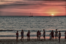 tourists on a beach at sunset 