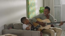 Happy father and son playing guitar. Family, parenthood, music and spending time together concept 