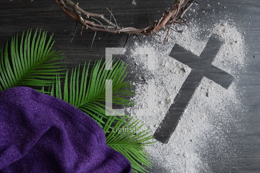 Lent background of ashes cross, crown of thorns, palm leaves and purple cloth