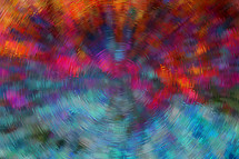 abstract background with spinning radial effect in turquoise, pink, orange, rust, green, blue