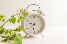 White alarm clock with white flowers on a white background