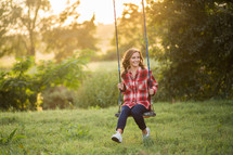 Teen girl on a swing outside.