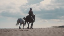 Horse riding on the beach, woman equestrian summer hack