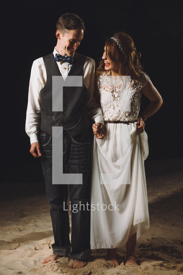 bride and groom standing in stand on a beach at night 