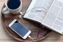 an open Bible and smartphone with earbuds 
