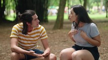 Angry couple with relationship problems fighting outside sitting in a park bench. Young couple having argument. Married people in fight