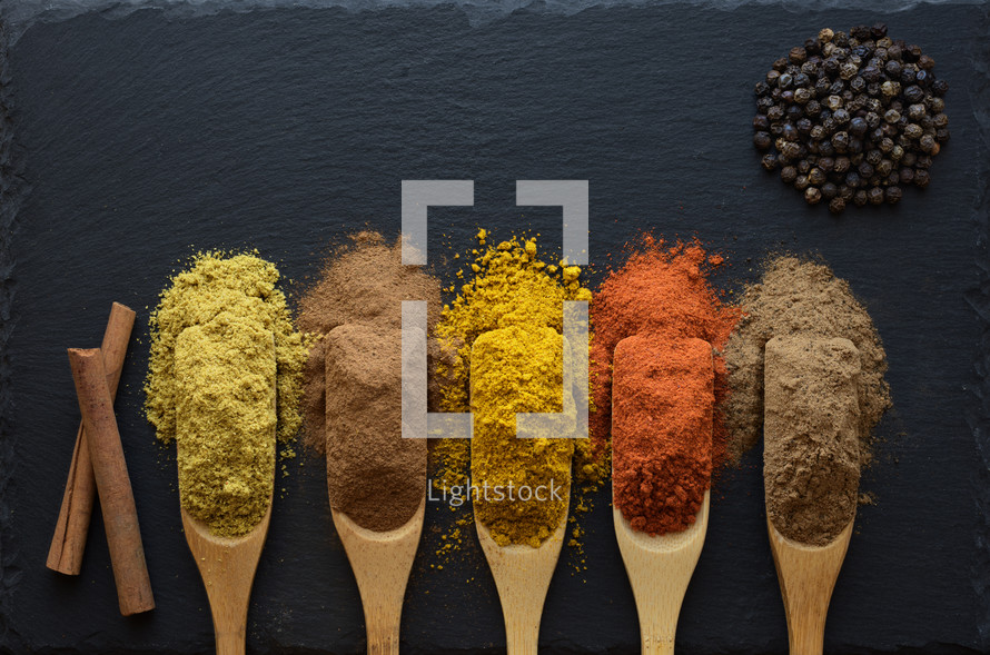 colorful herbs and spices in wooden spoons 