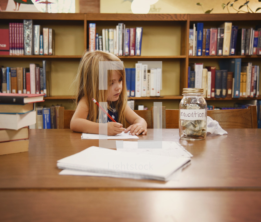 a child in a library doing homework next to a jar for education funds 
