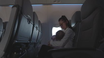 Mother holding infant daughter while flying on airplane - side profile in empty airplane
