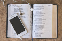 iPhone and earbuds on a Bible 