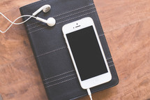 iphone and earbuds on a Bible 