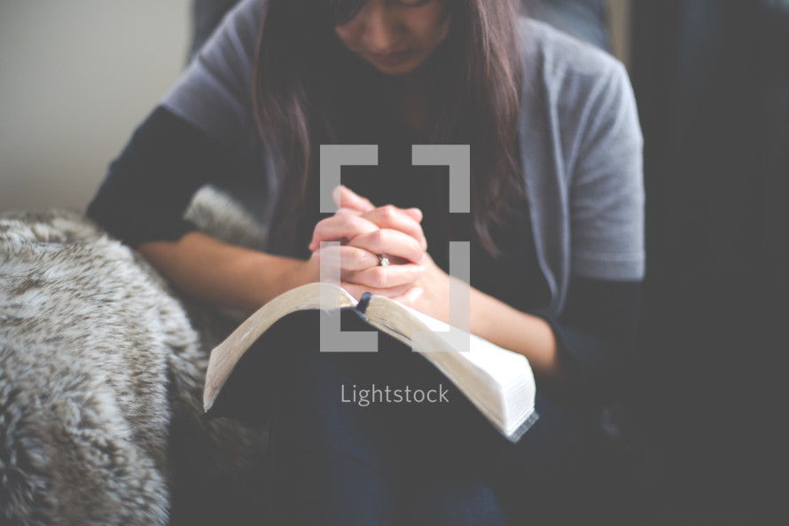 a woman praying over an open Bible 