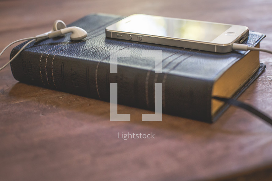 iphone and earbuds on a Bible 