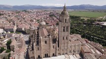 Closeup aerial orbit of Segovia Cathedral, vast countryside backdrop	