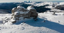 Aerial, orbit, drone shot around the sphinx rock formation, on the top of the southern Carpathians, on a sunny winter day, in the Bucegi Natural Park, Romania