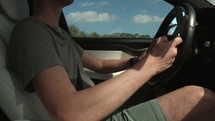 Man driving down road playing on smart phone in hand distracted driving - close up