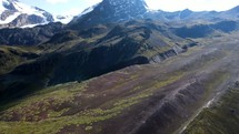 Aerial shot drone slowly ascends over mountain landscape with snow capped mountains