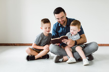 a Christian father reading a Bible to his sons 
