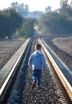 boy child walking alone on train tracks