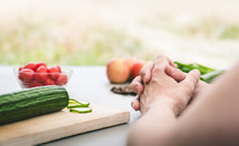 a man praying in front of vegetables on a cutting board 