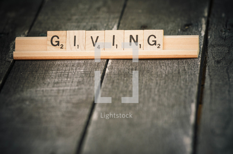"Giving" spelled in Scrabble tiles.
