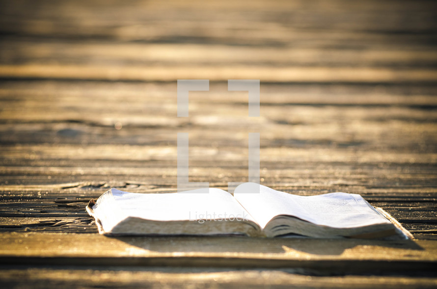 Open Bible on a wooden deck.