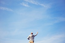 a man with a raised hand against a blue sky 
