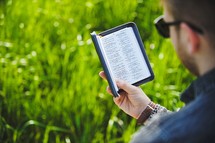 a man reading a Bible in the grass 