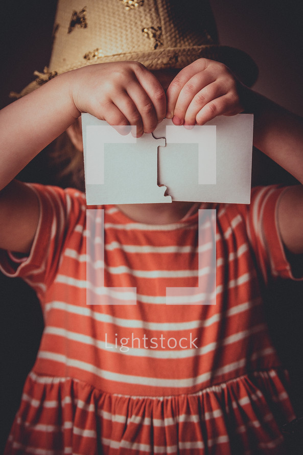 a child holding up blank puzzle pieces 